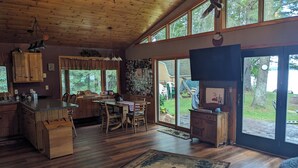 A spacious kitchen with wooden cabinets, a dining area with a table and chairs, and large windows offering a view of the outdoors.