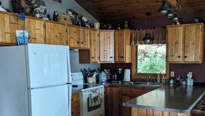 A kitchen with wooden cabinets, a white refrigerator, an oven, and a wooden island with a cutting board.