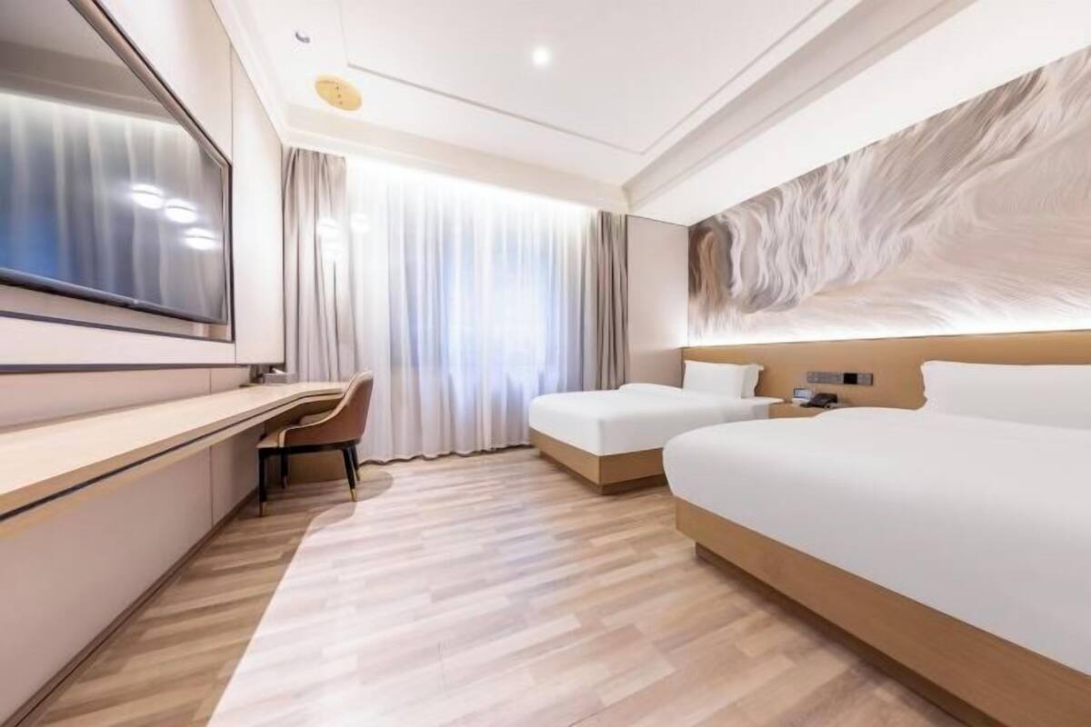 A hotel room with a large bed, a desk, a chair, and a TV.