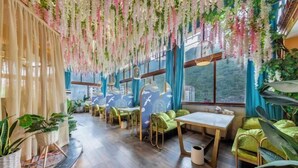 A restaurant with wooden flooring, green cushioned seating, and hanging floral decorations. - MAERkANG PO LING JIA SA HOTEL (Barkam)