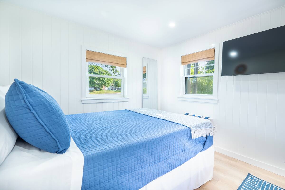 Une chambre à coucher avec un lit, une télévision et des fenêtres équipées de stores.