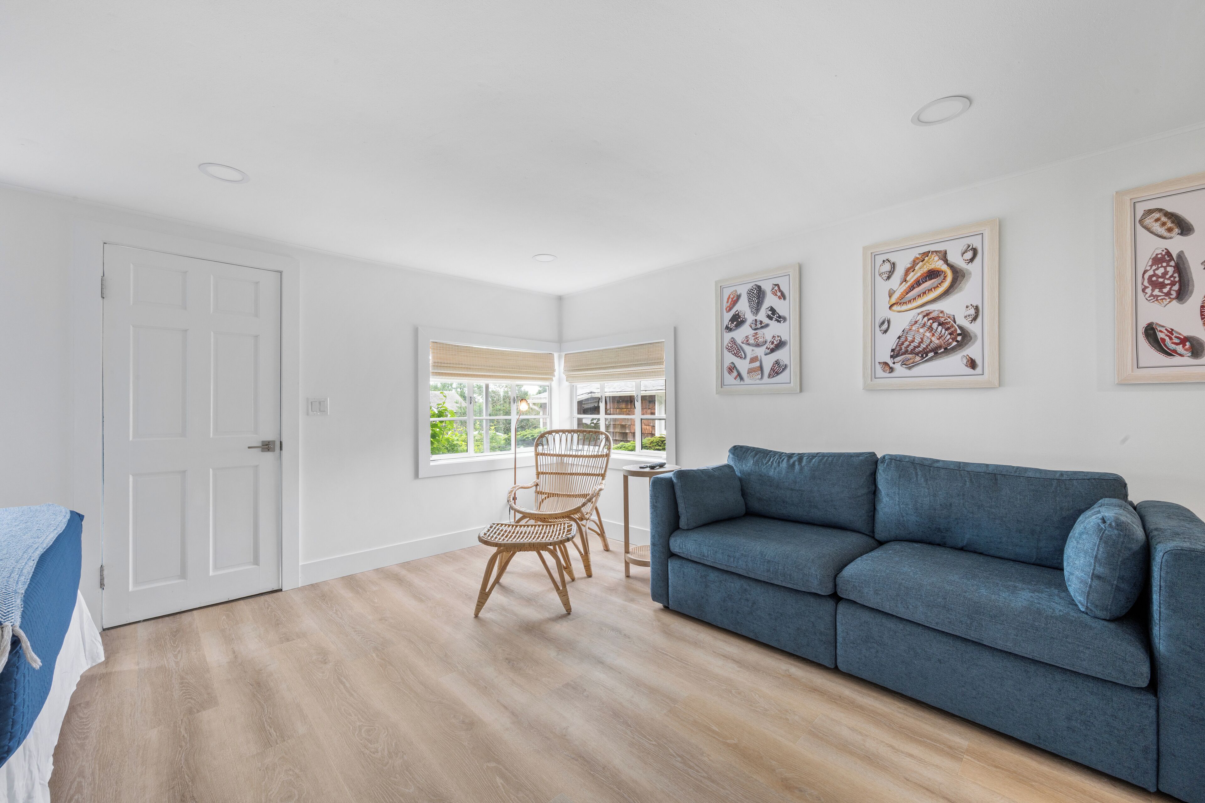 A spacious living room with a blue sofa, a dining area with wicker chairs, and framed artwork on the walls.