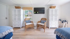 A bedroom with two wicker chairs, a TV, and two wardrobes.
