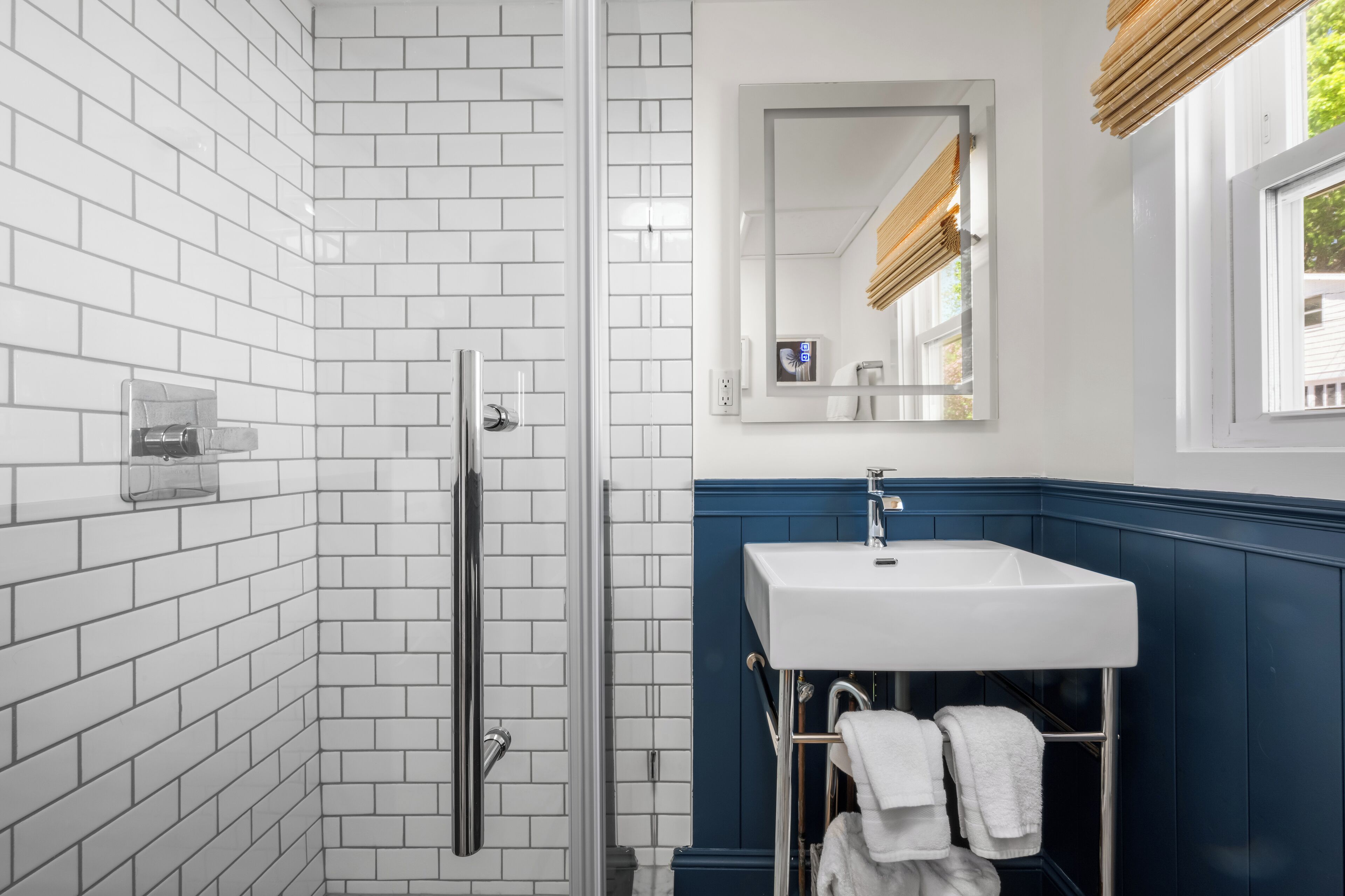 Een badkamer met witte betegelde wanden, een wit wastafel en een spiegel erboven.