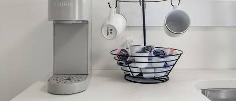 Una cafetera Keurig, una taza de café y un portavasos sobre una encimera cerca de una ventana.