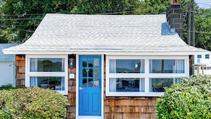 A small, single-story house with a blue door and multiple windows.