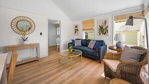 A modern living room with a sofa, wicker chairs, a round coffee table, and a console table with a mirror.