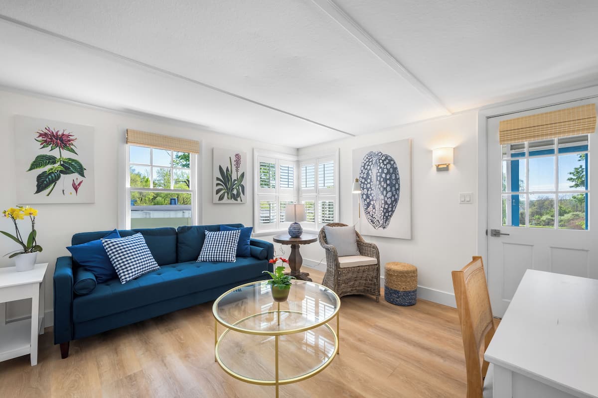 Un salon moderne avec un canapé bleu, une table basse en verre et un fauteuil en osier.