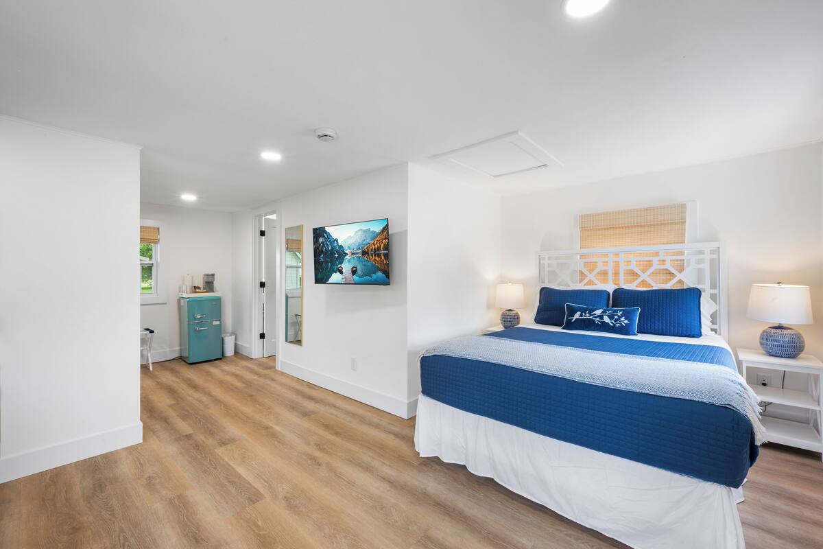 Une chambre à coucher avec un grand lit, une table de chevet, une lampe, un tableau au mur et une petite armoire.