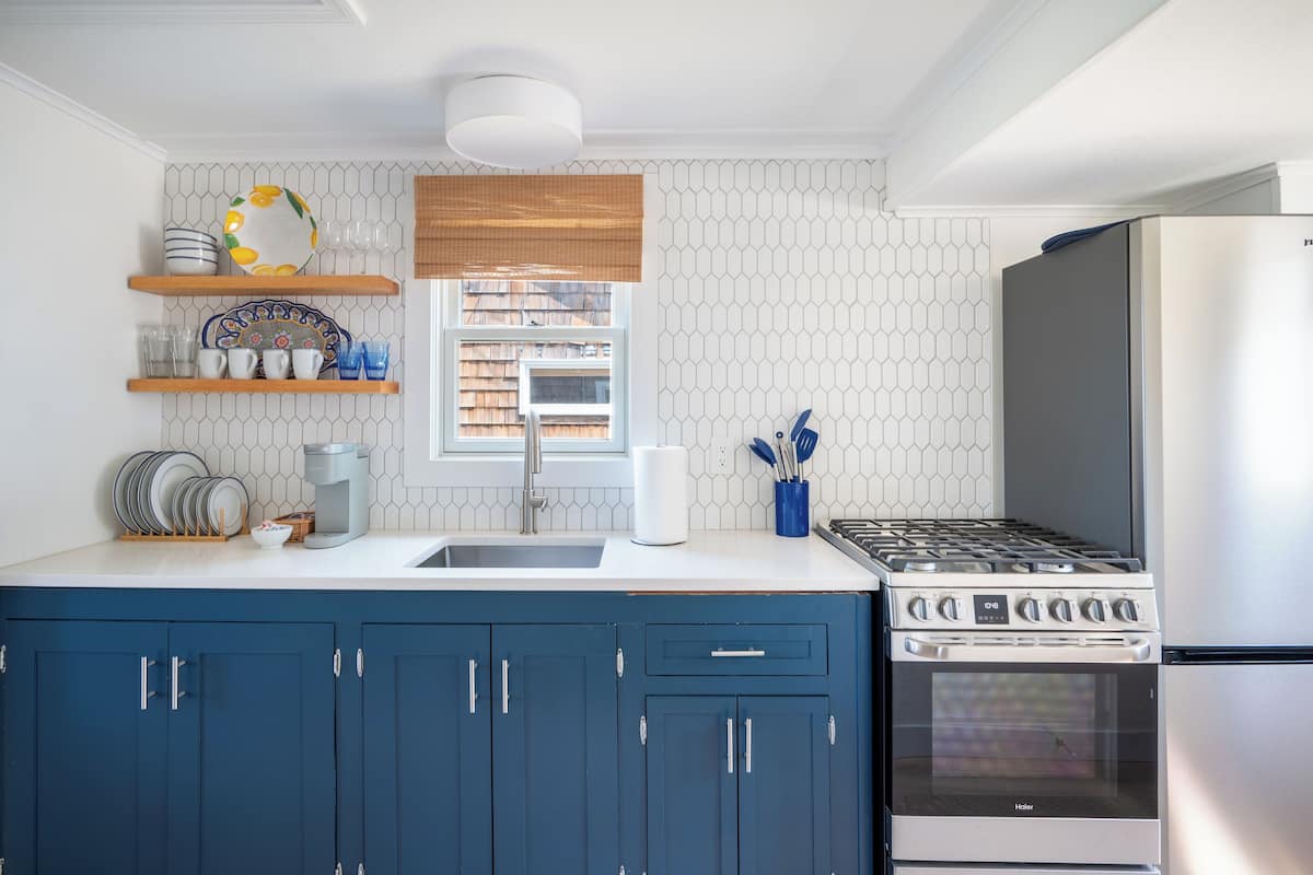 Une cuisine moderne avec des meubles bleus, une cuisinière, un four et un réfrigérateur.