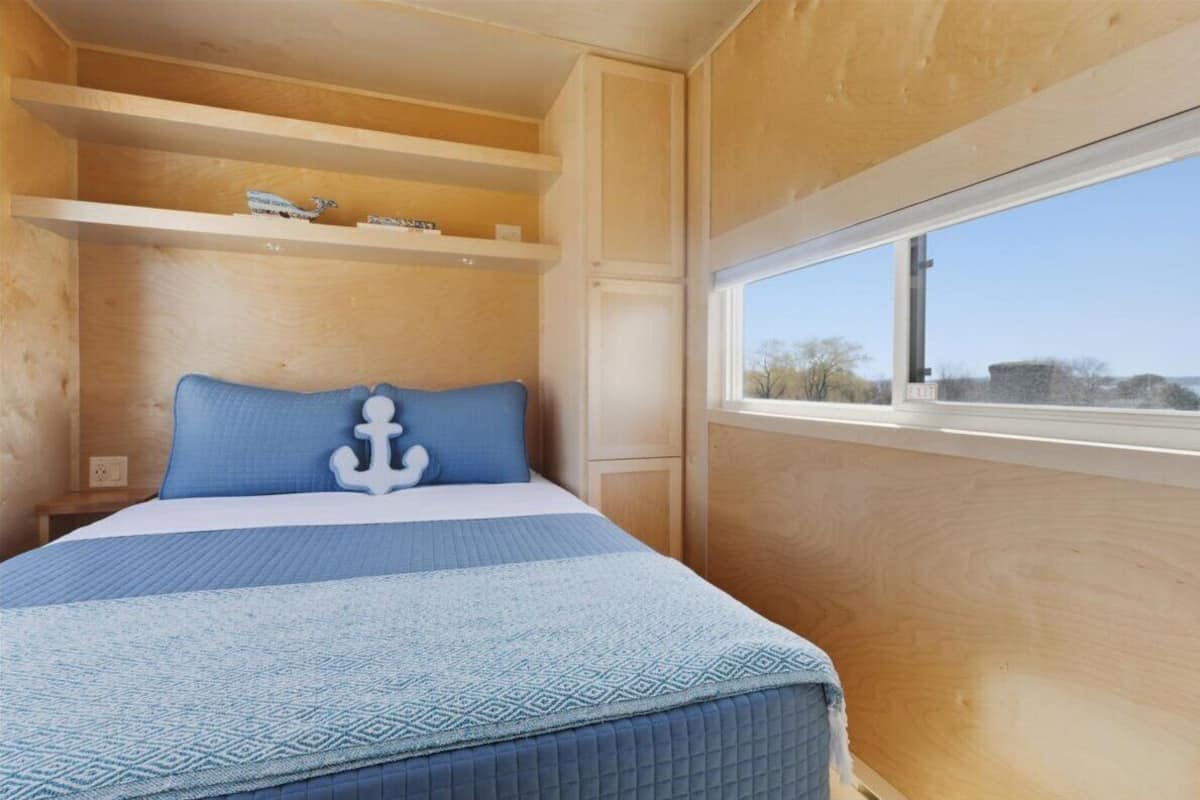 Une chambre à coucher avec un lit, une fenêtre et des étagères intégrées.