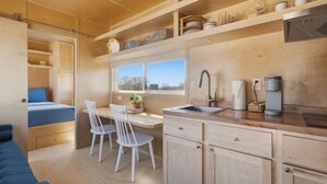 A compact kitchen with a sink, a coffee machine, and a window overlooking a natural landscape.