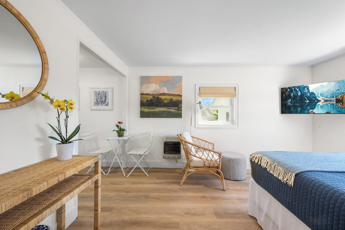 Une chambre à coucher comprenant un lit, un bureau en bois, une chaise, un radiateur et une fenêtre donnant sur un paysage.