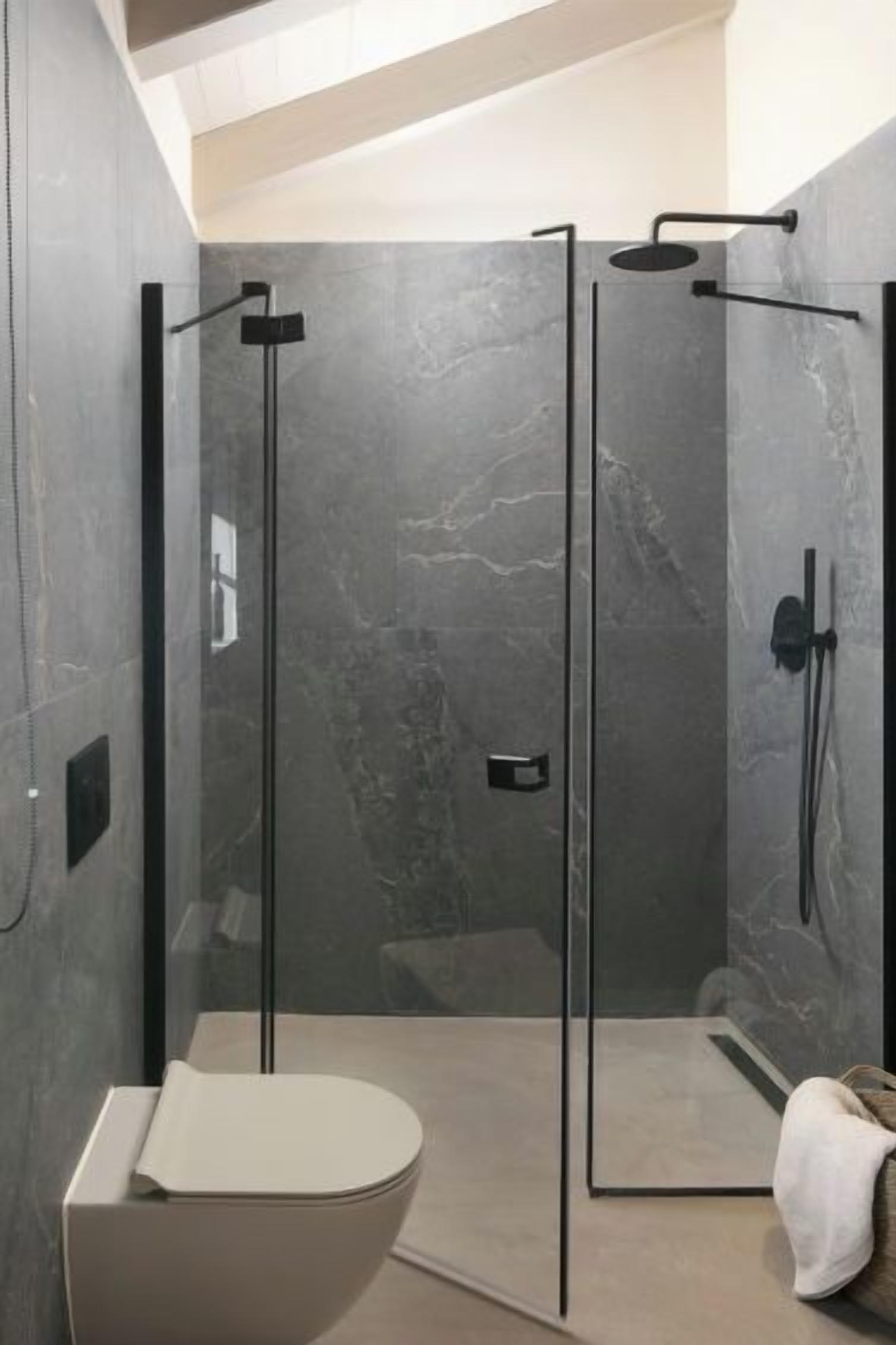 A modern bathroom with a glass-enclosed shower, a minimalist toilet, and a towel on the floor.