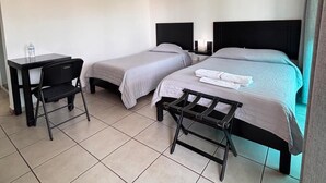 A hotel room with two beds, a desk, a chair, and an air conditioning unit. - HOTEL CASCADA (Cuautla)