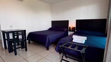 Habitación de hotel con dos camas, una mesita, una silla y un tendedero.