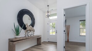 A hallway with a wooden bench, a large mirror, and a potted plant. - Newly Built Home w/ Fresh Design! (Columbia)