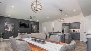 A modern kitchen with grey cabinets, a stainless steel refrigerator, and a built-in oven. - Newly Built Home w/ Fresh Design! (Columbia)
