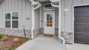 A residential building with a gray exterior, a stone foundation, a white front door, and a garage door. - Newly Built Home w/ Fresh Design! (Columbia)