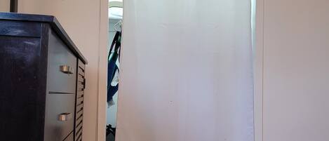 A room with a wooden floor, a metal dresser, and a white curtain.