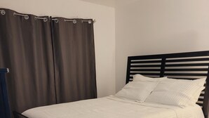 Ein Schlafzimmer mit einem Bett, Vorhängen und einem dunklen Teppich.