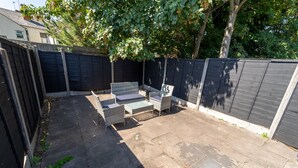 A backyard patio with a seating area, a table, and a small garden bed. - Stunning 1-Bed Studio in Birmingham available (Birmingham)