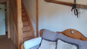 Puisesta sängystä on leikattu sydämenmuotoinen aukko, siinä on puinen pääty ja seinälle on ripustettu pari hiihtosuksea.