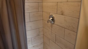 A shower with a wooden wall, a showerhead, and a curtain. - Downtown Cozy Castlerock Suite (Wenatchee)