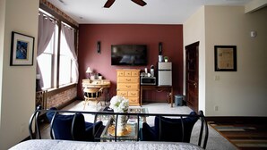 A living room with a ceiling fan, a television, a wooden cabinet, and a dining area with a table and chairs. - Downtown Cozy Castlerock Suite (Wenatchee)