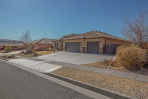 Houses with tile roofs and garages line a well-manicured neighborhood.