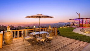Une terrasse en bois avec une table et des chaises, une lanterne et une vue sur le paysage.