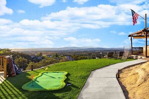 Ein Golfplatz mit Blick auf ferne Berge, eine Fahne und ein Fahnenmast.