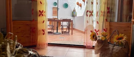 A room with a wooden floor, a dining table with chairs, a white umbrella, and a basket with sunflowers.