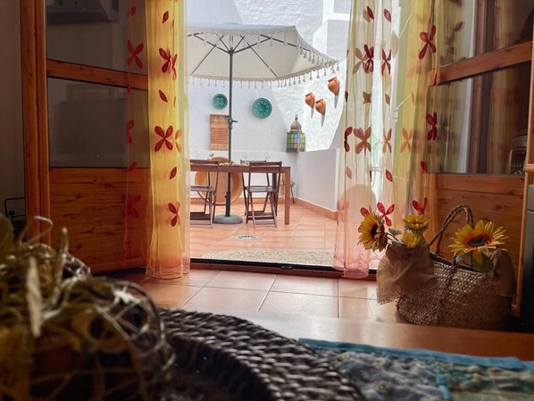 Une pièce avec un plancher en bois, une table à manger avec des chaises, un parapluie blanc et un panier rempli de tournesols.
