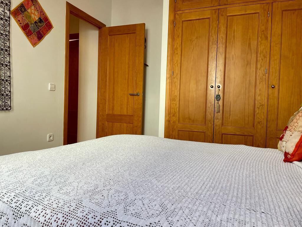 Un dormitorio con una cama grande, un armario de madera y una puerta que da a otra habitación.