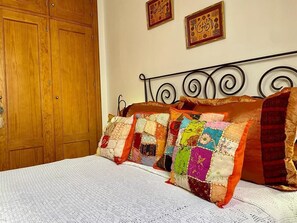 Un lit avec un drap blanc et plusieurs oreillers de couleurs vives.