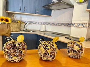 Three decorative baskets on a wooden table in a kitchen with blue cabinets and white tiled backsplash. - Rubire Apartment in Vejer (Vejer de la Frontera)