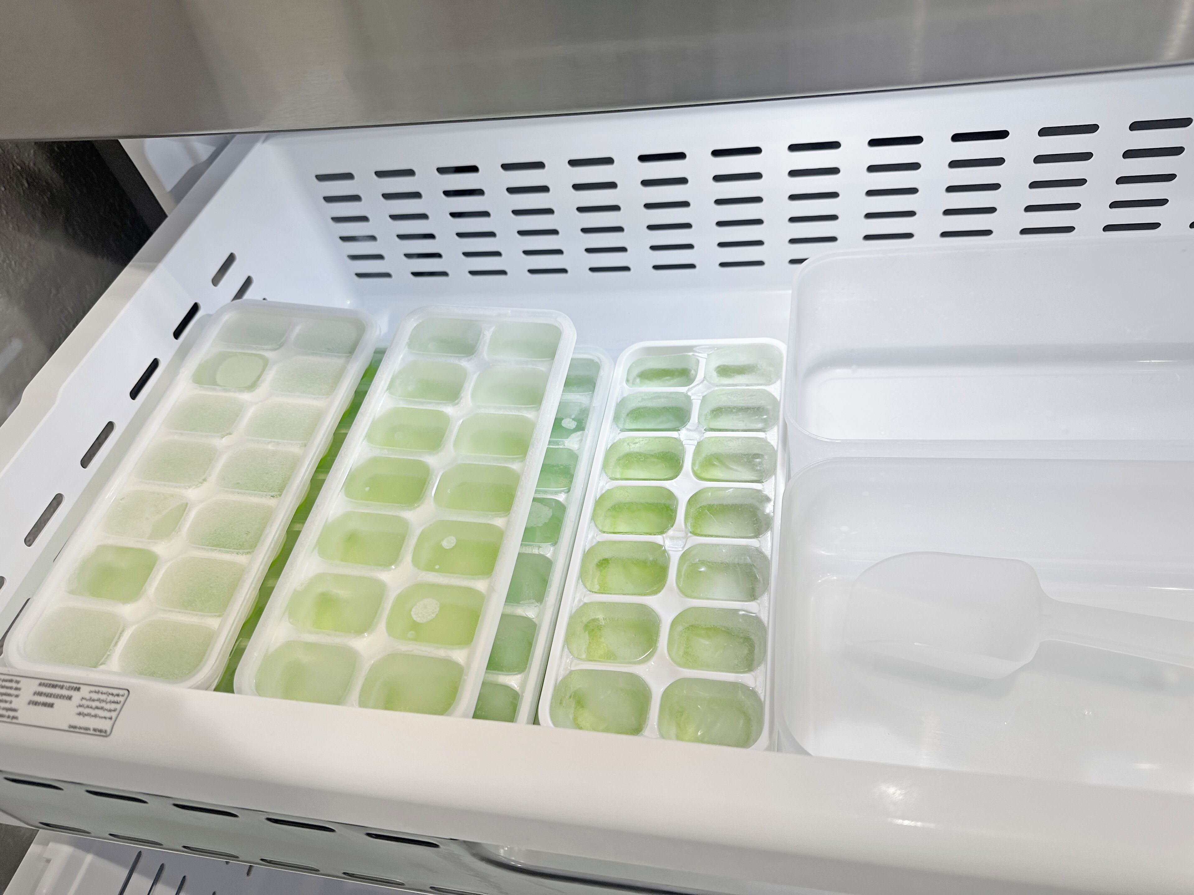 A freezer with multiple compartments containing ice cubes.