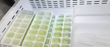 A freezer with multiple compartments containing ice cubes.