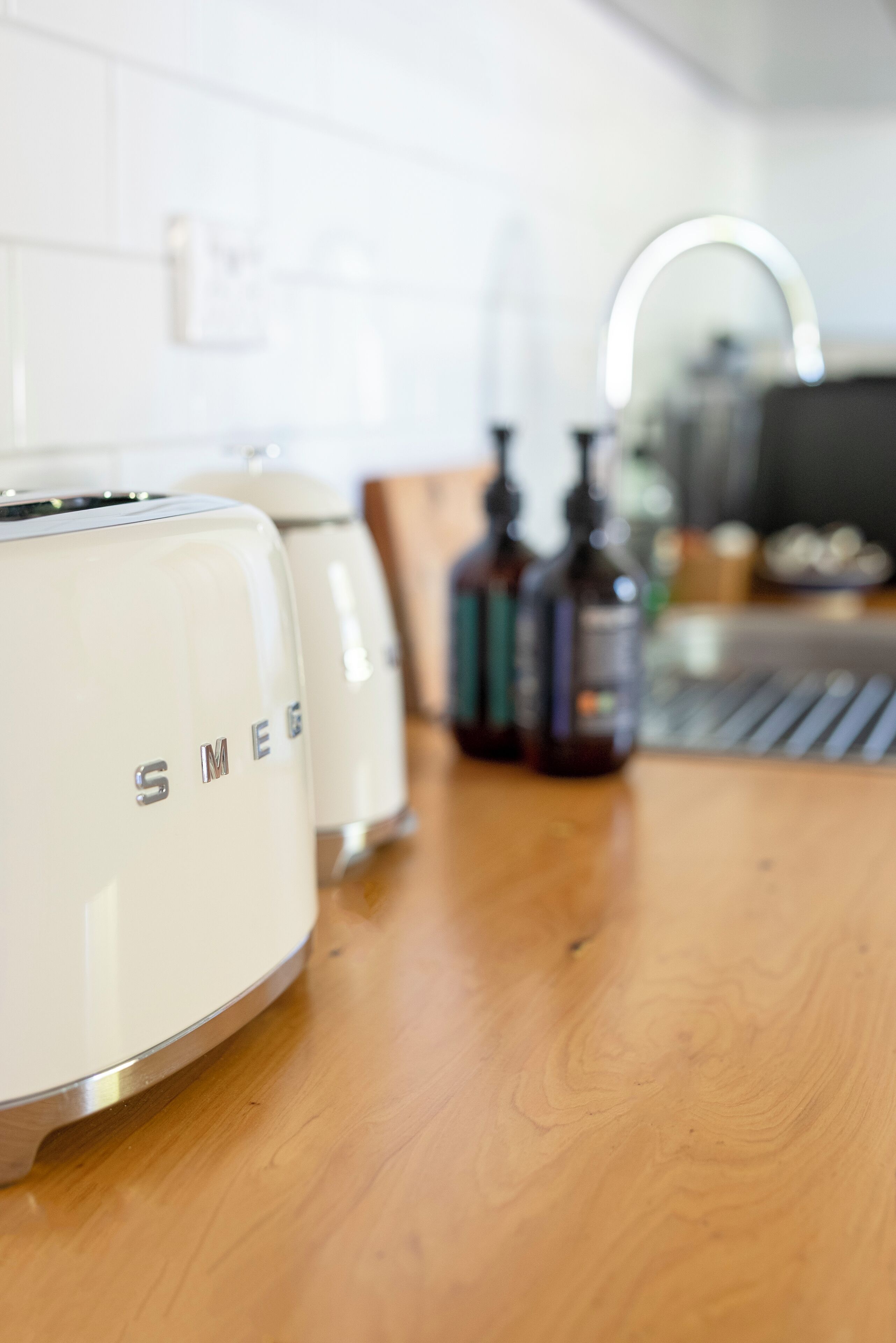 A kitchen with white appliances, a wooden countertop, and a sink with a mirror above it.
