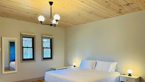Une chambre à coucher comprenant un lit, deux tables de chevet, une commode, un miroir et un plafond en bois.
