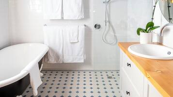 A bathroom with a bathtub, a shower, a sink, and a mirror.