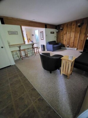 Relax in a comfortable seating area with a sofa and armchairs, plus a bar area with stools.