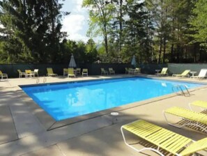 Relax by the pool surrounded by a deck and lush greenery.