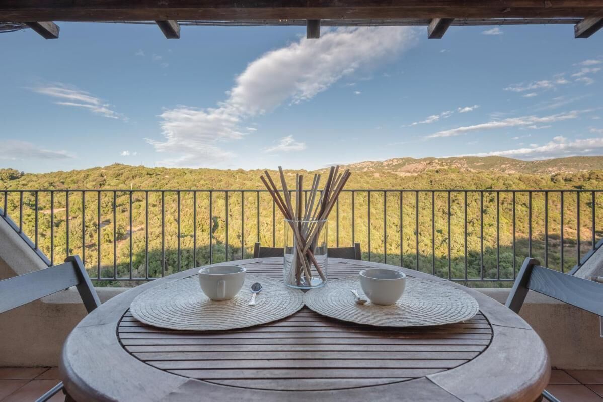 Una mesa con dos cuencos y un vaso de agua en un balcón con vista a un paisaje montañoso.