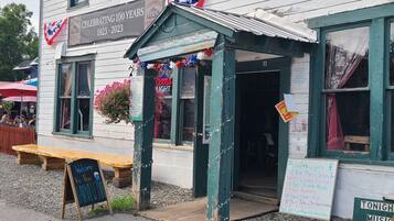 A historic building with a sign celebrating 100 years, outdoor seating, and a signboard for live music events.