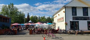 A historic inn with a sign celebrating 100 years, outdoor seating, and bicycles parked outside.
