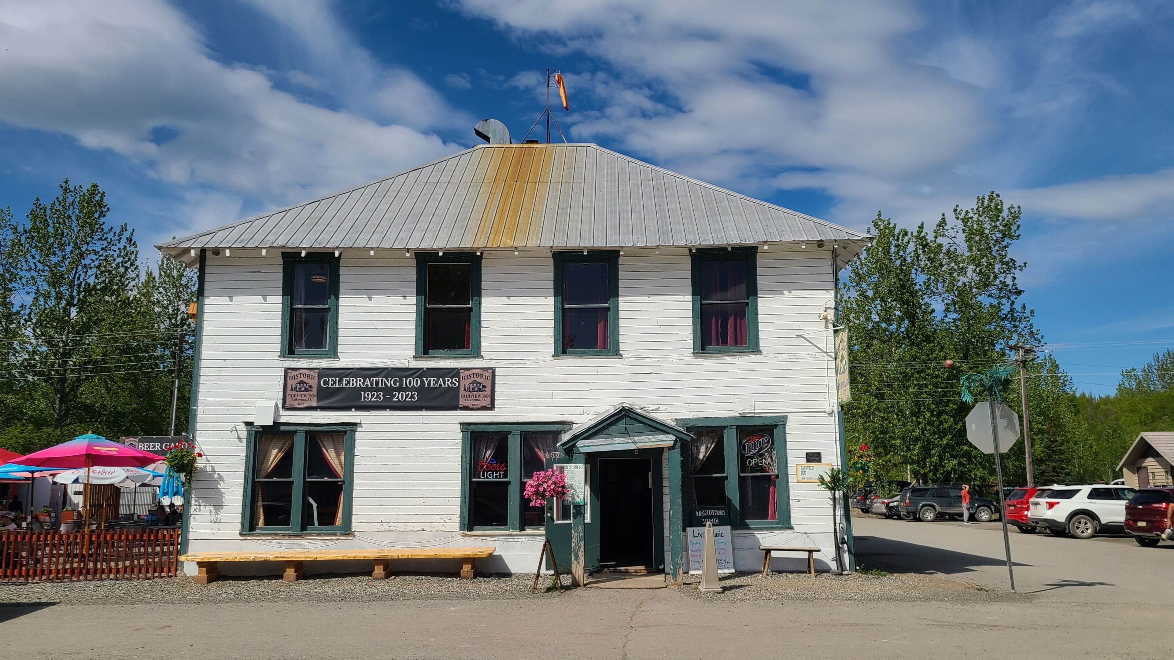Un bâtiment historique, orné d’une plaque commémorative célébrant son centenaire, doté d’un jardin à bière et d’un panneau indiquant qu’il propose des concerts.
