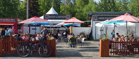 An outdoor market with food stalls and tents, including a 'Beer Garden' and 'Merchandise' tent.