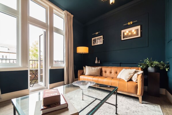 Un salon avec une table basse en verre, un canapé en cuir et une grande fenêtre.